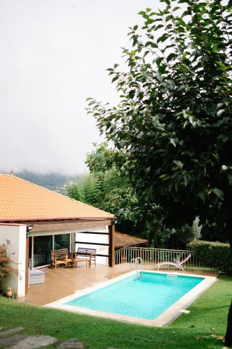 a swimming pool in a yard next to a house at Casa da Assudra in Vila Verde