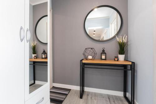 a hallway with two console tables and a mirror at Rybacka 48 - Twoje miejsce wypoczynku, domki, studia, apartamenty, rowery, hulajnogi in Jantar