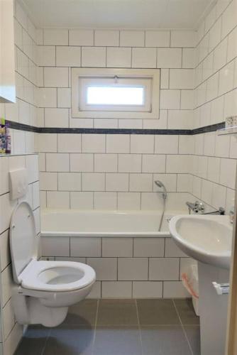 a white bathroom with a toilet and a sink at Cosy Sjalay near the lake for 6-8 persons in Büchel