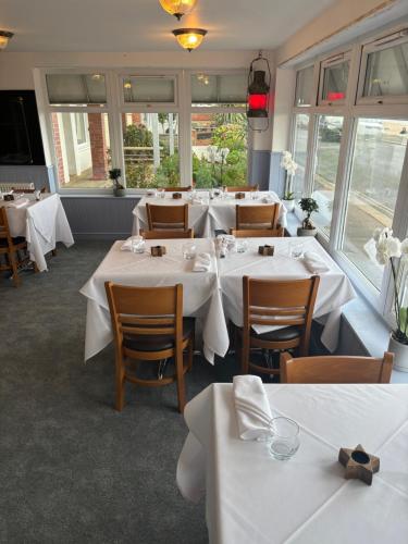 a restaurant with white tables and chairs and windows at Navigator Hotel in Bognor Regis