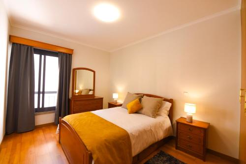 a bedroom with a bed and a mirror and a window at Farinha's Apartment in Ribeira Brava
