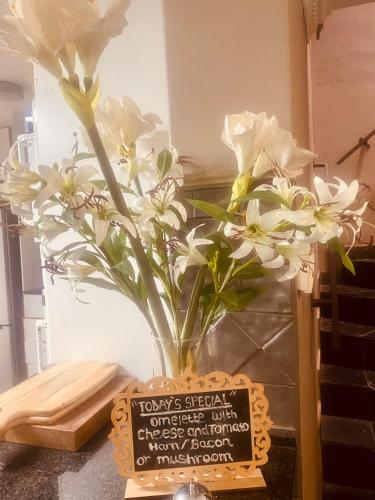 a vase filled with white flowers sitting next to a sign at Boord Guest House in Stellenbosch
