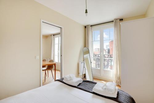 une chambre avec un lit et une grande fenêtre dans l'établissement Pick A Flat's Apartment in Saint-Ouen - Rue des Rosiers, à Saint-Ouen