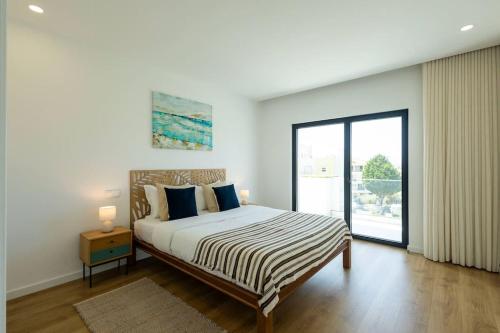 a bedroom with a bed and a large window at Villa Pessegueiros in Ericeira