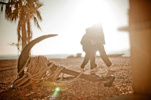 a pair of shoes on the beach with a person in the background at Hotel San Antonio in Podstrana