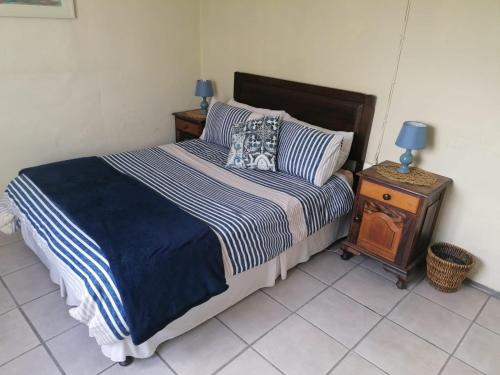 a bedroom with a bed and a night stand with a lamp at Arniston Cottage in Arniston