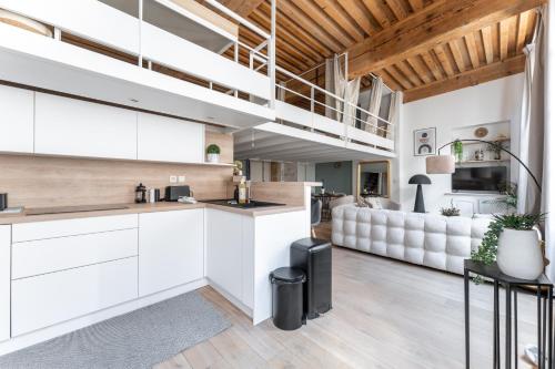 une cuisine avec des placards blancs et un salon avec un canapé dans l'établissement MDOR - Atoll - Appt au cœur de Lyon, à Lyon