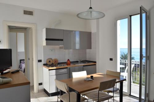 a kitchen with a table and a dining room with a view at Residence Villa Carmen fronte mare a 50 mt in Pietra Ligure