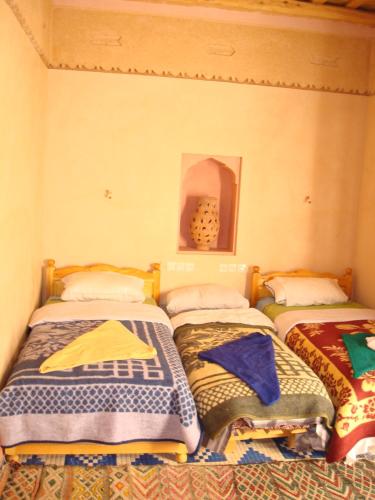 two beds in a room with colorful blankets at Kasbah Ait Kassi in Boumalne