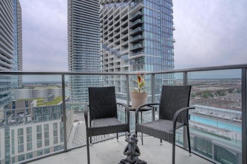 two chairs on a balcony with a view of a city at Wonderland Apartment in Vaughan in Vaughan
