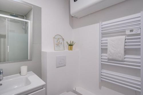 une salle de bain blanche avec un lavabo et un miroir dans l'établissement MDOR Le Chai - Appt au cœur de Bordeaux, à Bordeaux