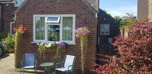a house with two chairs and a window with flowers at Mermaid Cottages in Frinton-on-Sea