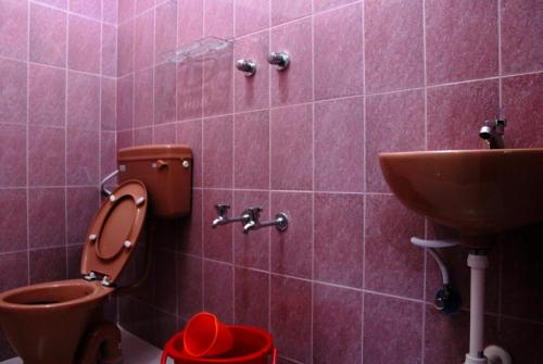 un bagno rosa con servizi igienici e lavandino di Vinodhara Guest House a Mamallapuram