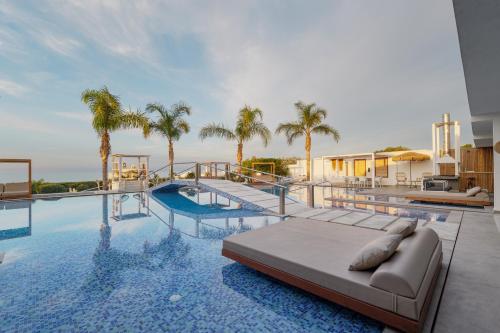 una piscina con sofá y palmeras en White Luxury Villa, en Hersonissos