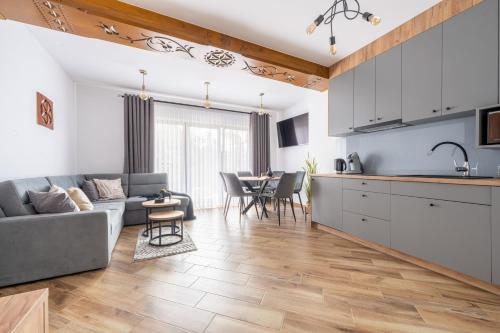a kitchen and living room with a couch and a table at Para Apartments - Dwupoziomowe Apartamenty in Biały Dunajec