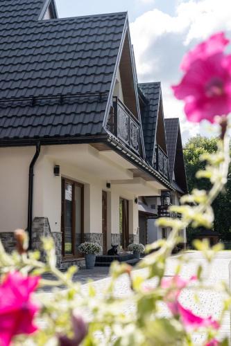 a house with a balcony and pink flowers at Para Apartments - Dwupoziomowe Apartamenty in Biały Dunajec