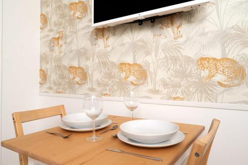 - une table en bois avec 2 assiettes et des verres à vin dans l'établissement Charming studio in Versailles - Welkeys, à Versailles