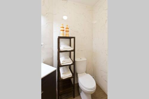 a bathroom with a toilet and a shelf with towels at Matosinhos House Surf & Beach in Matosinhos