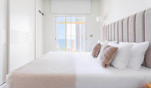 une chambre blanche avec un grand lit avec des oreillers blancs dans l'établissement Intempo by Holuxe - 045 - 4th floor, à Benidorm