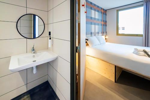 a bathroom with a sink and a bed with a mirror at easyHotel Marseille Euromed in Marseille