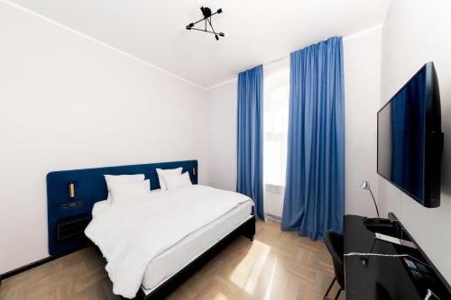 a bedroom with a bed and a tv and blue curtains at TRIBE Riga City Centre in Rīga