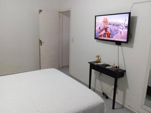 a bedroom with a bed and a tv on the wall at Casa confortável com amplo espaço a 800 m da praia in Porto Belo