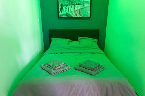 a green bed with two towels on top of it at Résidence grand jardin attenant tennis, mini golf, sauna, pétanque in Cucq