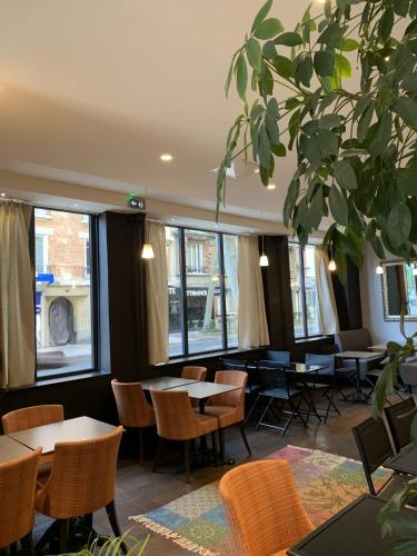un restaurant avec des tables, des chaises et des fenêtres dans l'établissement Hotel Sixteen Paris Montrouge, à Montrouge