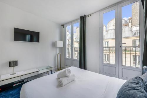une chambre blanche avec un lit et une grande fenêtre dans l'établissement Moulin Rouge Terrasse, à Paris
