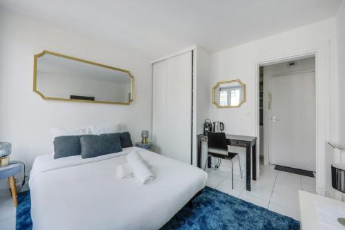 - une chambre avec un lit blanc, un bureau et un miroir dans l'établissement Moulin Rouge Terrasse, à Paris