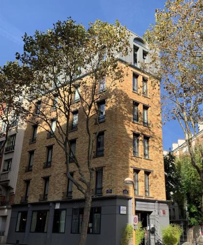 a brick building with a tree in front of it at Hotel Sixteen Paris Montrouge in Montrouge