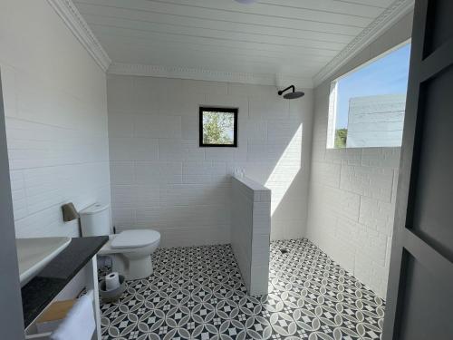 a white bathroom with a toilet and a window at Bushbuck Farm Eco-Retreat in Humansdorp
