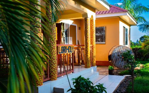 a yellow house with a gate and a palm tree at Msamaria Lori Hostel in Moshi