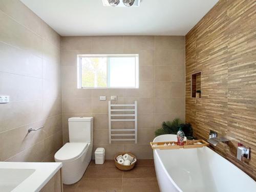 a bathroom with a tub and a toilet and a sink at Lake-view Retreat w Spa, nearby Beaches & Shopping in the Central Coast in Lakeside