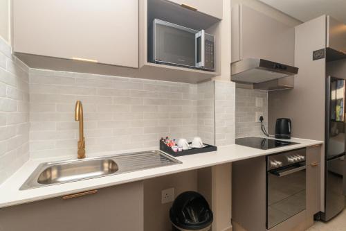 Una pequeña cocina con fregadero y microondas. en Cans BlackBrick lux, en Johannesburgo