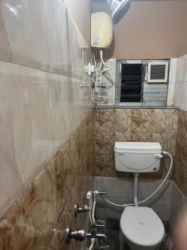 a bathroom with a toilet and a air conditioner at Lodge Babul in Kolkata