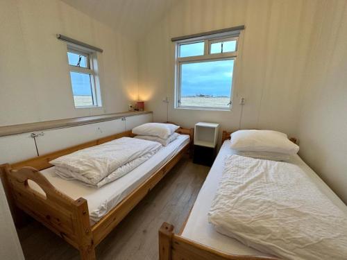 two twin beds in a room with a window at Cave Cabins in Hella