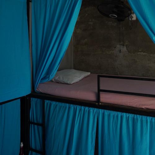 a bed in a tent with a blue curtain at Cycling Backpacker Hostel in Unawatuna