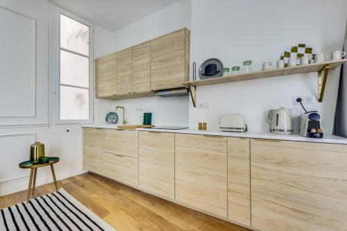 une cuisine avec des armoires en bois et une fenêtre dans l'établissement L'émeraude - Neuf & Calme -Opéra & Grands Magasins, à Paris