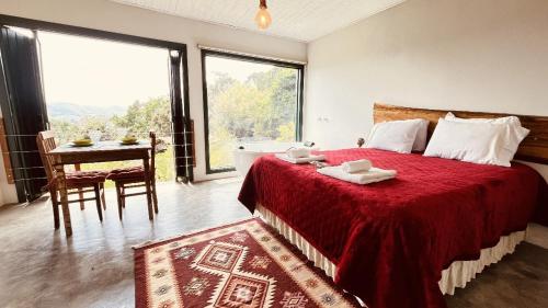 a bedroom with a bed with a red blanket and a table at Montanha Home in Monte Verde