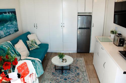 a living room with a blue couch and a table at 185 on BEACH Boutique Suites in Gordonʼs Bay