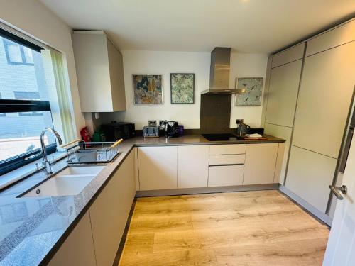 a kitchen with white cabinets and a sink and a window at #13 Elegant Solihull Townhouse - Sleeps 10 - NEC BHX - "Perfect for Contractors and Families - Fee Parking in Olton
