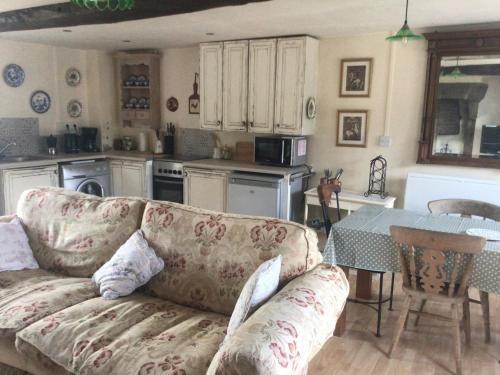 un salon avec un canapé et une table dans une cuisine dans l'établissement La sourdine, à Sourdeval