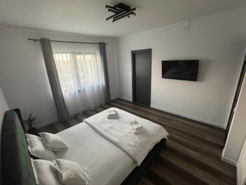 a bedroom with a bed with white sheets and a window at Casira Guesthouse in Sînmartin