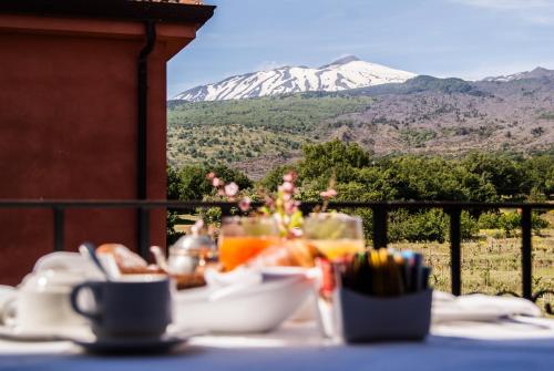 a table with a plate of food with a mountain in the background at Picciolo Etna Golf Resort & Spa, Curio Collection by Hilton in Castiglione di Sicilia