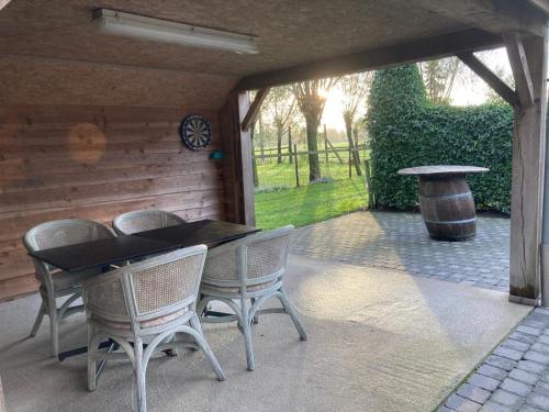a patio with a table and chairs and a barrel at De Smokkelaar & Het Schuurtje in Maldegem