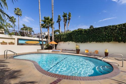 a swimming pool with chairs and trees and a building at Pacific Edge Hotel in Laguna Beach