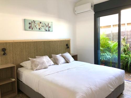 a bedroom with a large white bed and a window at Pervenche in Saint-Pierre