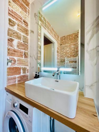 La salle de bains est pourvue d'un lavabo blanc et d'un mur en briques. dans l'établissement 202 - Chaleureux appartement proche centre ville, à Belfort