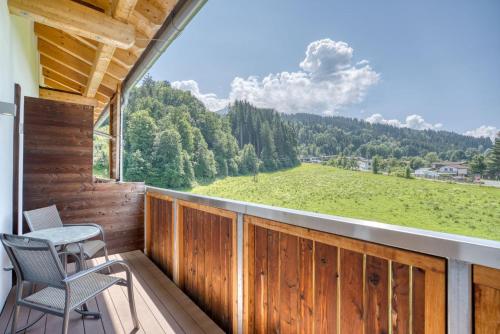 a balcony with two chairs and a large window at COOEE alpin Hotel Kitzbüheler Alpen in Sankt Johann in Tirol